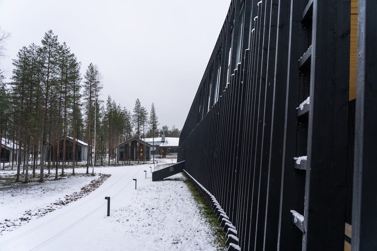 The outside of Nova Skyland at Santa Claus Village
a photo of black wood around a hotels perimeter with a snowy landscape