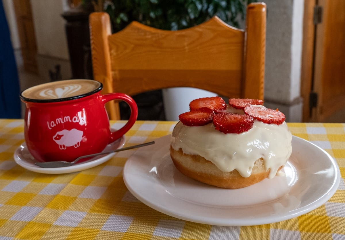 Donuts and Coffee in Bukhara
a photo of a white chocolate doughnut with strawberries on top and a flat white on a table