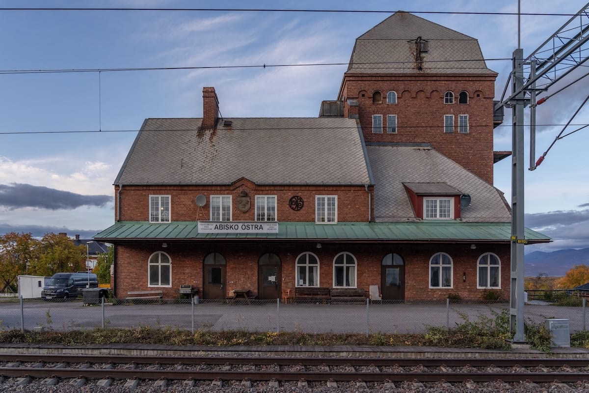 How to get from Kiruna to Abisko ; Abisko Östra station - a train platform wiht a brick train station.