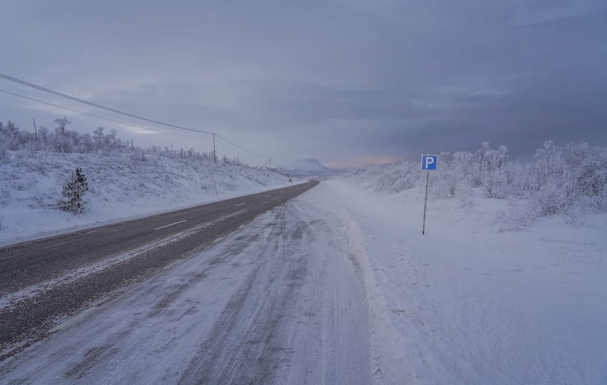 a snowy road with a parking sign in a snowy landscape in northern sweden