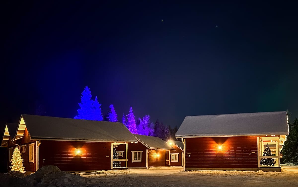 Santa Claus Holiday Village cabins in the winter
red cabins under a dark sky with neon lights in forest