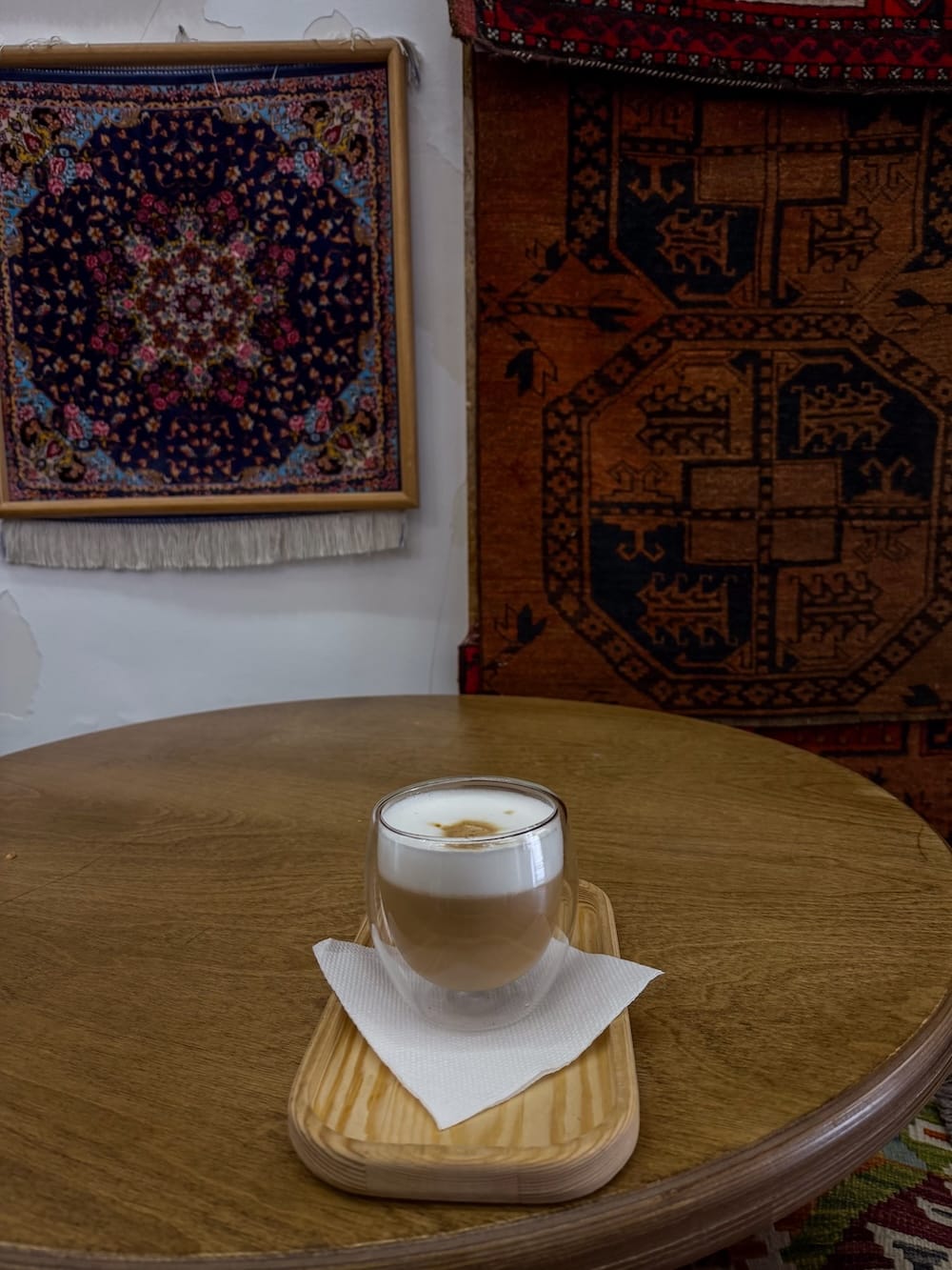 Coffee at Magic House
a glass cup of coffee on a table with uzbek carpets behind it