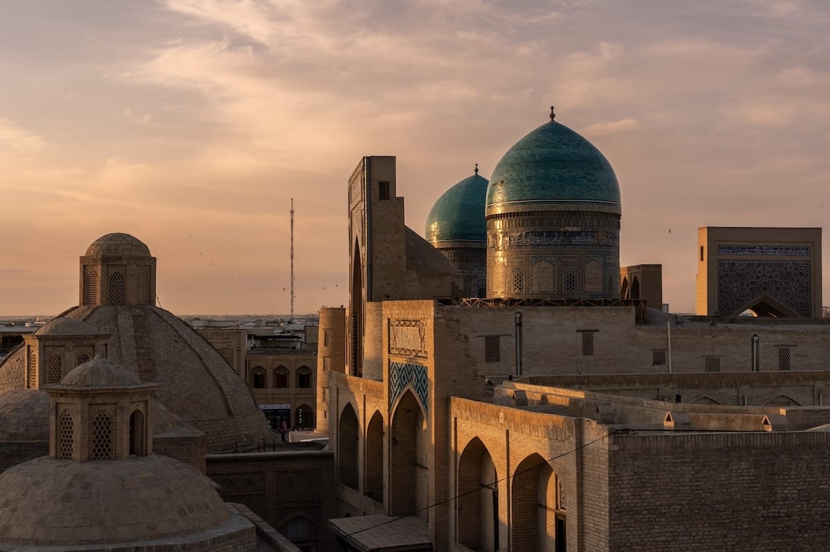 Sunset view of turquoise domes and old town rooftops from Minorai Kalon Restaurant and Terrace in Bukhara, Uzbekistan