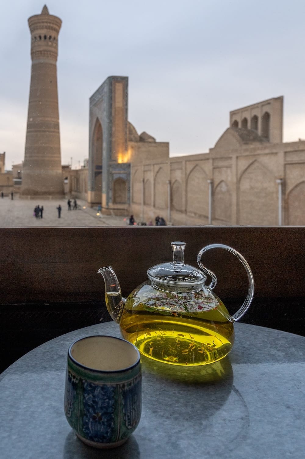 A pot of tea at Pavillon in Bukhara
a clear teapot and glass beside a window overlooking historic bukhara, uzbekistan