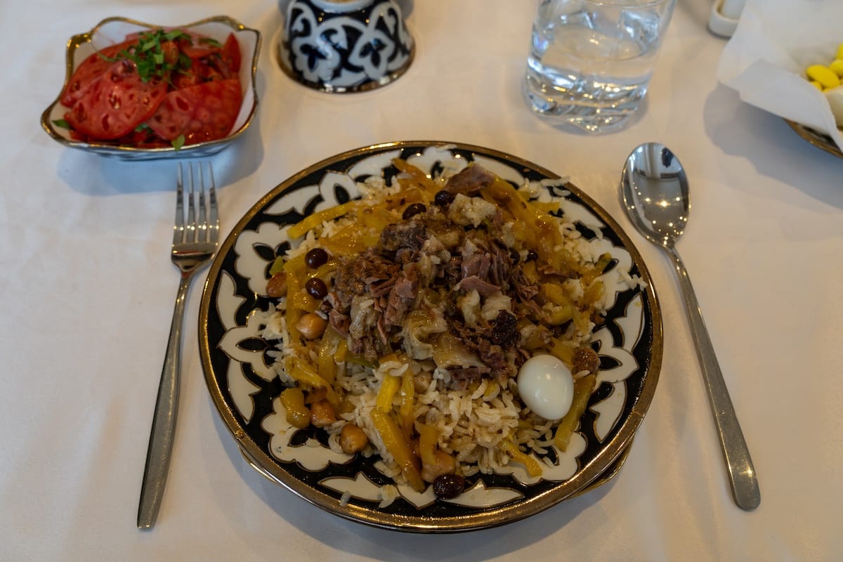Plate of Bukhara-style plov with meat, egg, raisins, and chickpeas in Uzbekistan