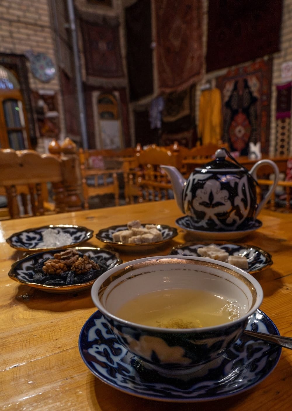 Tea at Silk Road Teahouse
a pot of tea with a cup with green tea in it, and many small plates with uzbek sweets