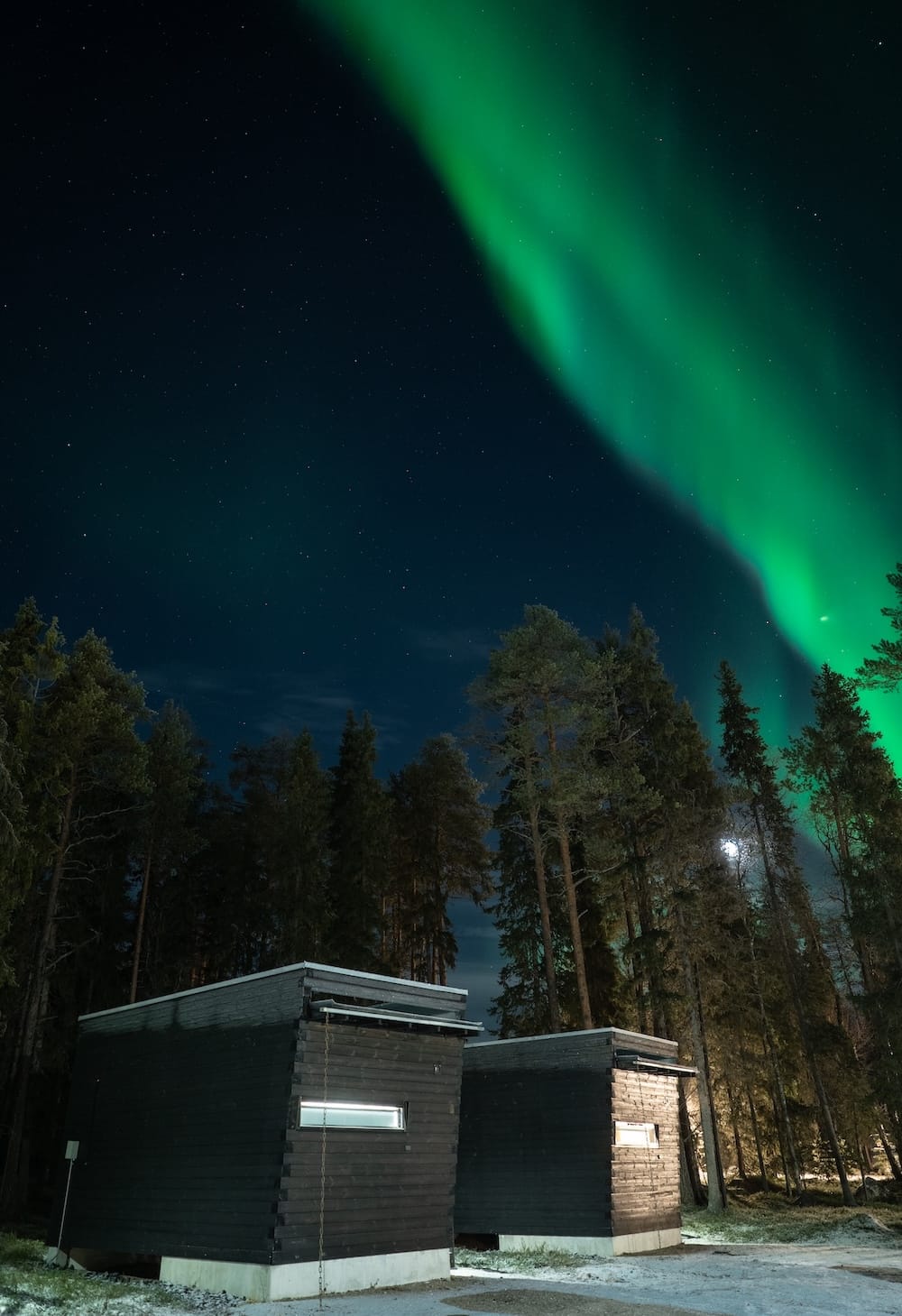 Vaattunki Wilderness Resort in Rovaniemi
the northern lights over black cabins in a forest in finland