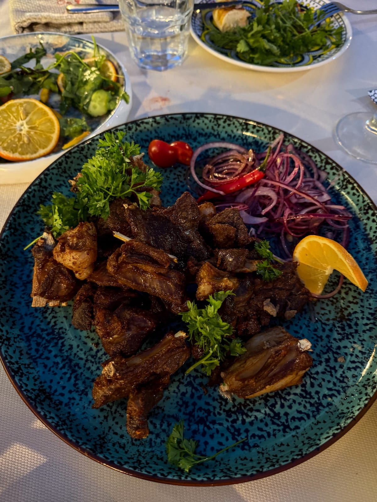 Plate of vaguri lamb ribs with onion and herbs at Old Bukhara Restaurant in Bukhara, Uzbekistan