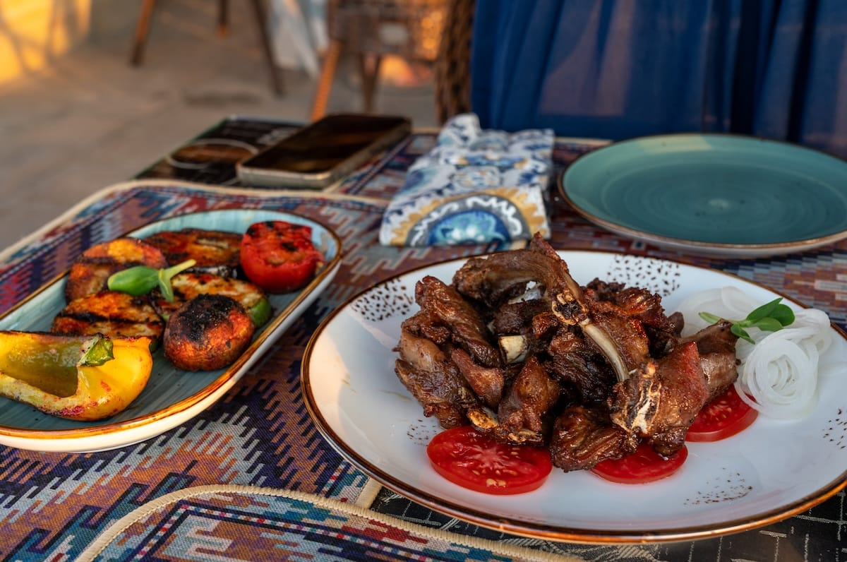 Plate of vaguri grilled lamb ribs with tomato and onion at a restaurant in Bukhara, Uzbekistan Where to eat in Bukhara | Restaurants in Bukhara