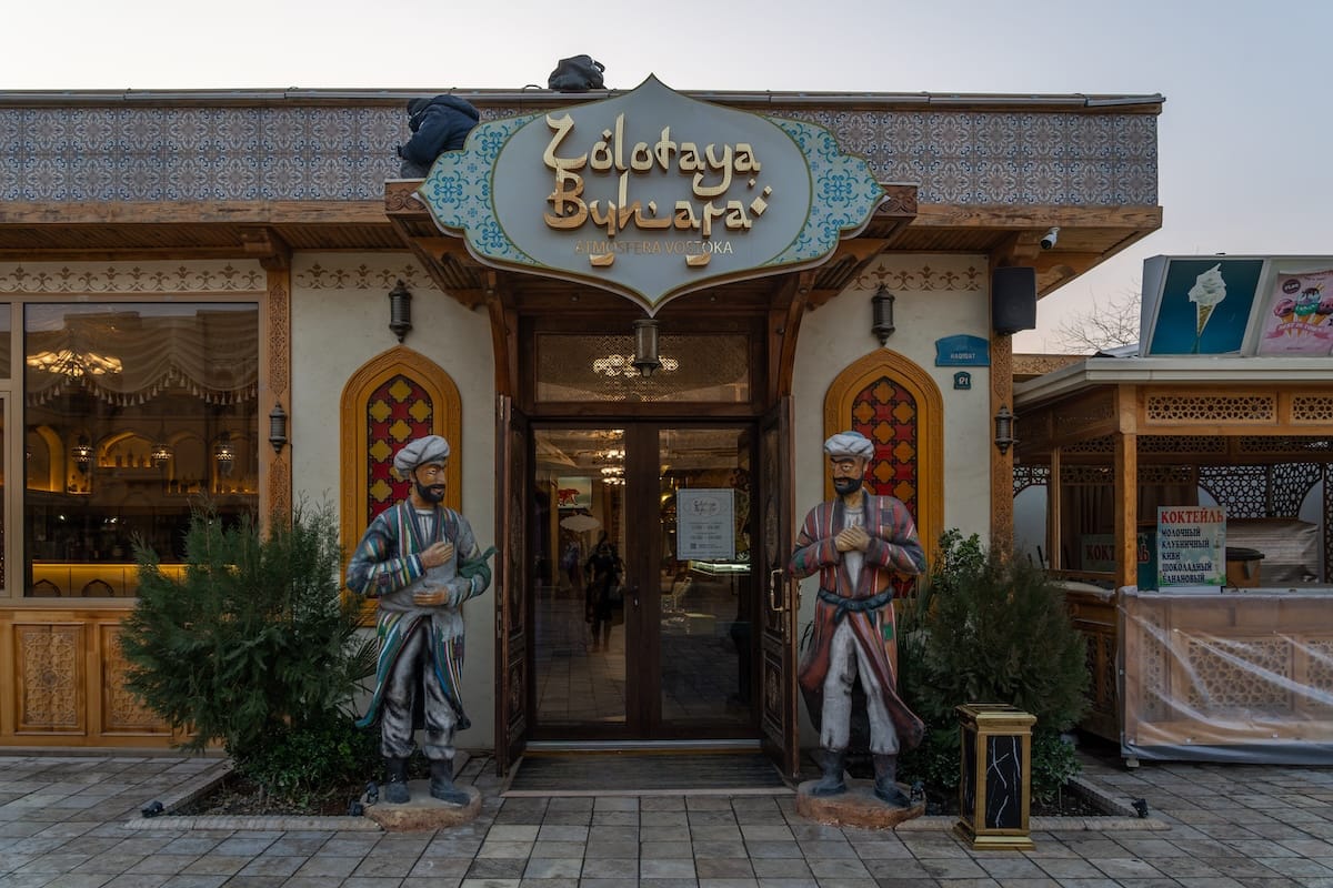 Entrance of Zolotaya Buhara restaurant with statues in traditional Uzbek dress in Bukhara, Uzbekistan