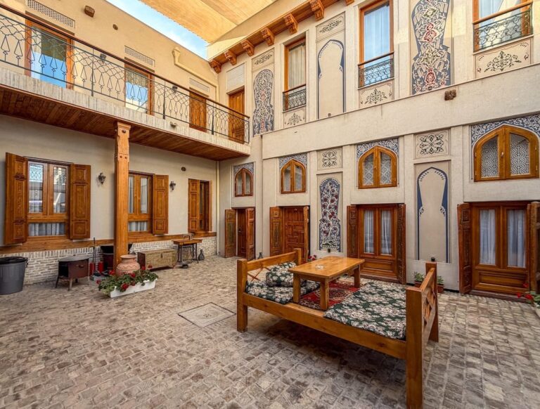 Where to stay in Bukhara (best Bukhara hotels) Courtyard with a wooden tapchan seating platform and painted facades at Duston Boutique Hotel in Bukhara, Uzbekistan