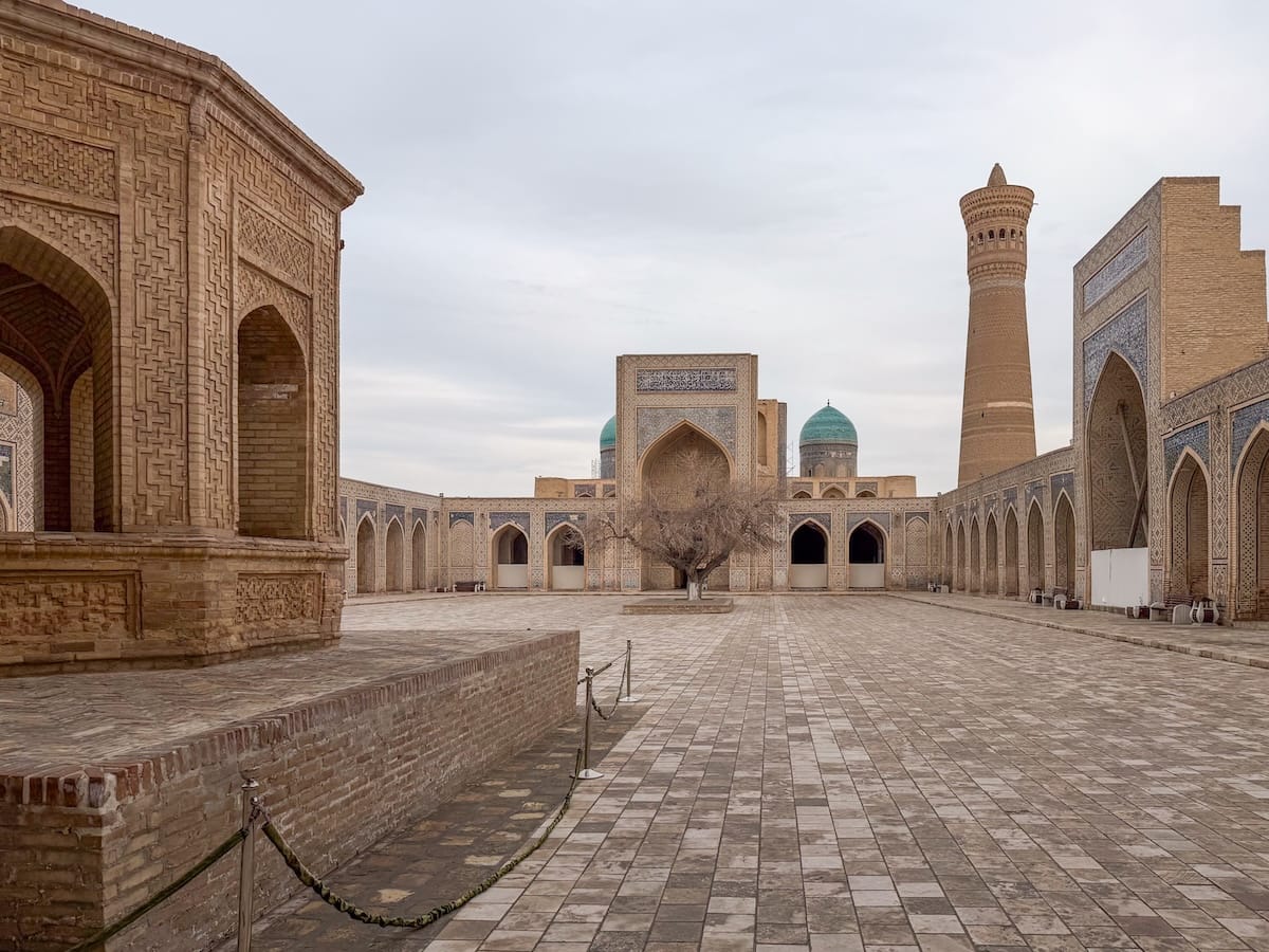 Bukhara in winter (the empty Kalan Mosque)

Empty courtyard of the Kalyan Mosque in Bukhara with the Kalyan Minaret, turquoise domes, and carved brick arcades under an overcast winter sky