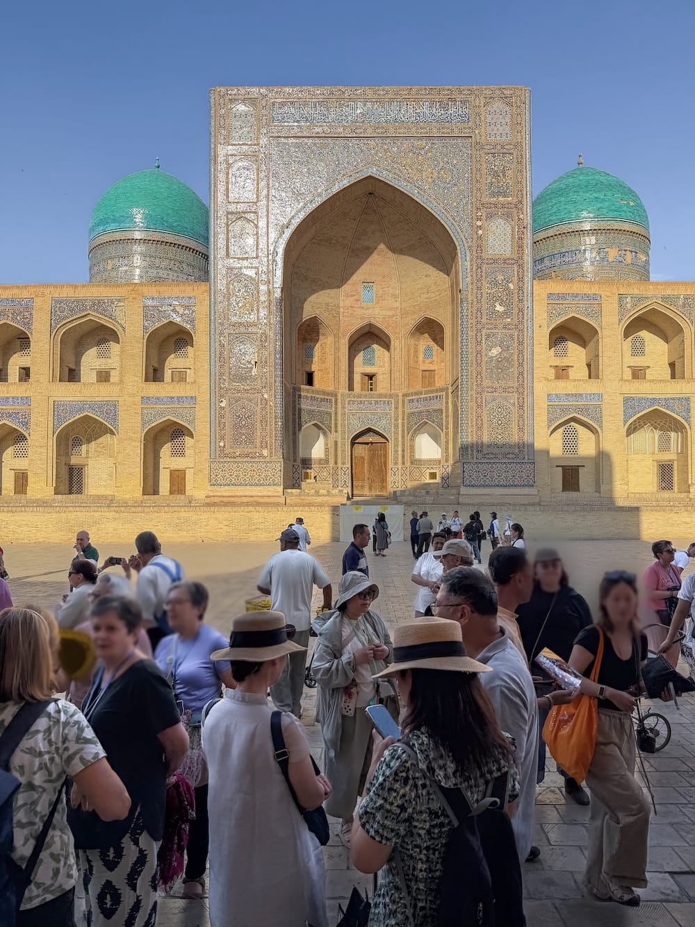 Crowd of tourists gathered in front of the Mir-i-Arab Madrasah in Bukhara waiting to get inside Kalan Mosque