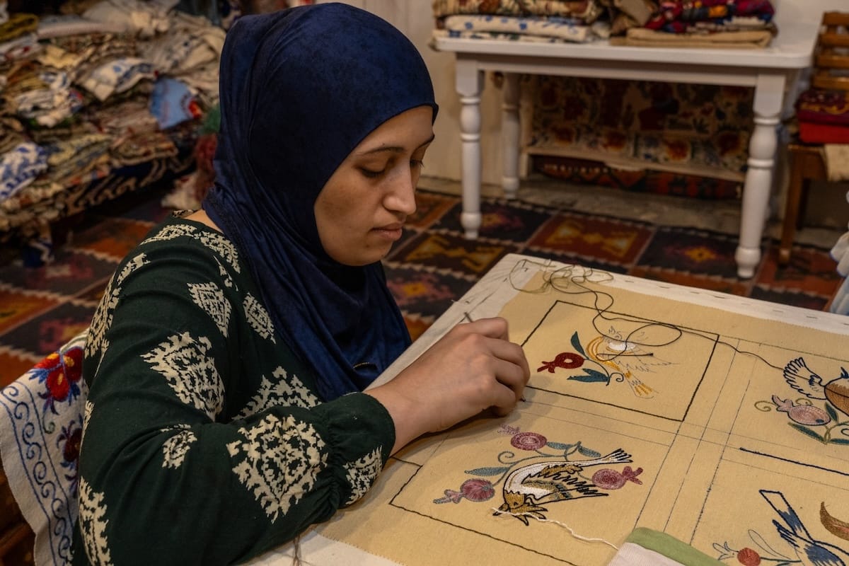 Artisan hand-embroidering a floral and bird suzani design at Craft&Culture workshop in Bukhara, Uzbekistan
